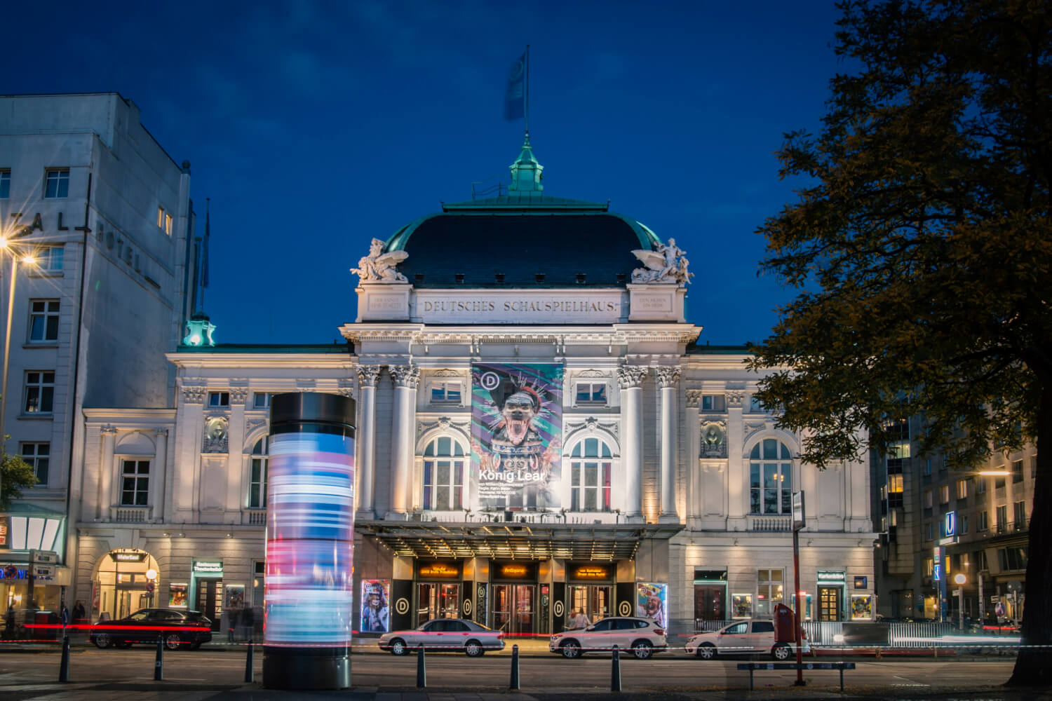 Man sieht das Deutsche Schauspielhaus Hamburg. Fotografiert ist der Haupteingang bei Dämmerung.