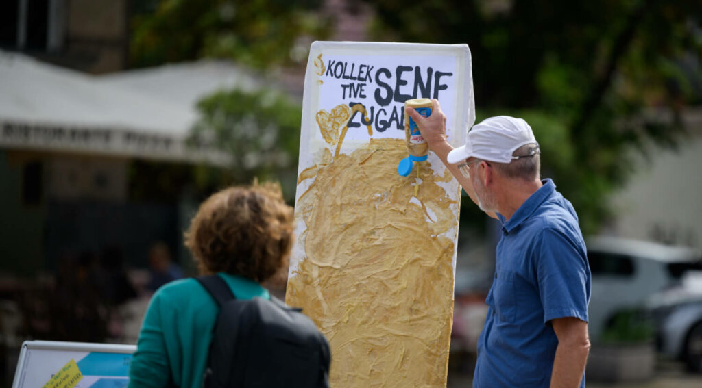 Menschen streichen ein Plakat mit Senf ein