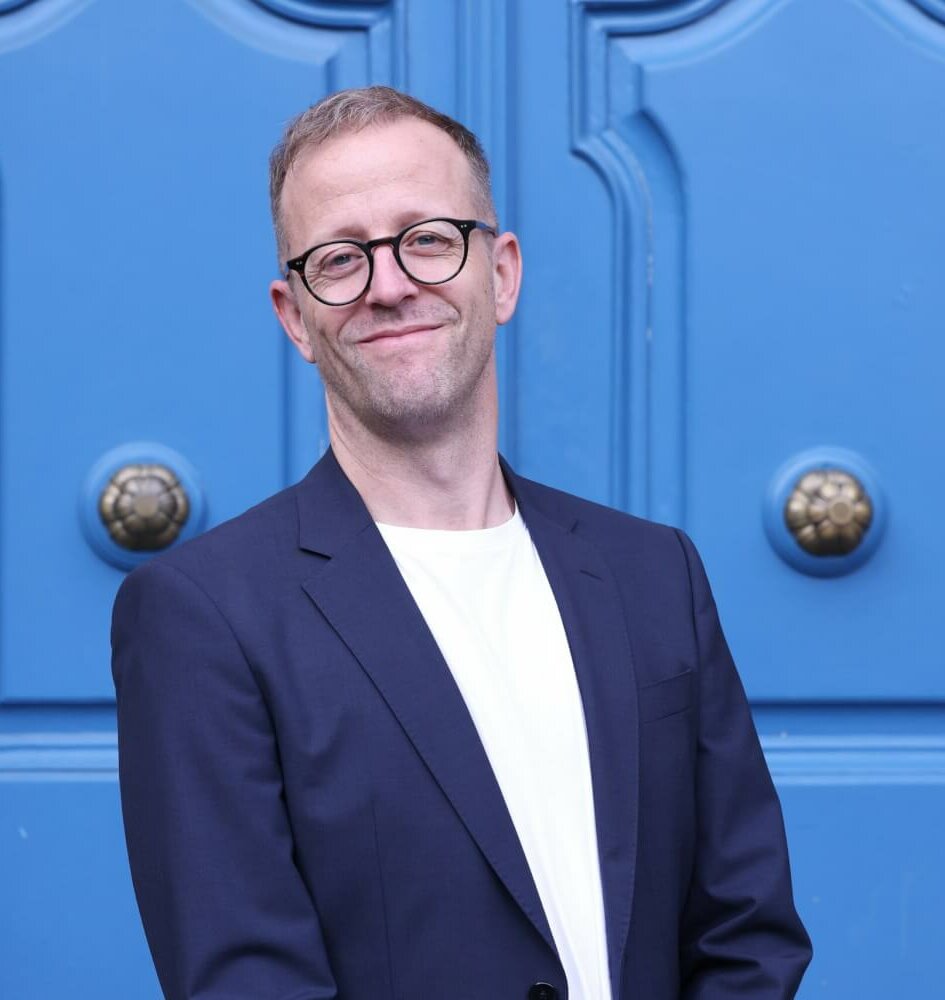 Vor einer blauen Tür ist Andreas Karlaganis, designierter Intendant des Düsseldorfer Schauspielhauses, zu sehen.