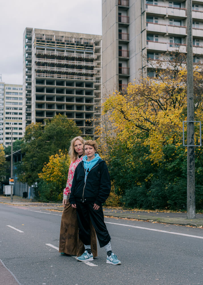 Mille Maria Dalsgaard und Mareike Mikat auf einer Straße in Halle-Neustadt, vor Plattenbau-Hochhäusern